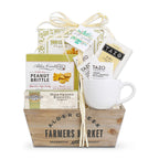 Gift basket with a mug, snacks, and tea packages on a white background