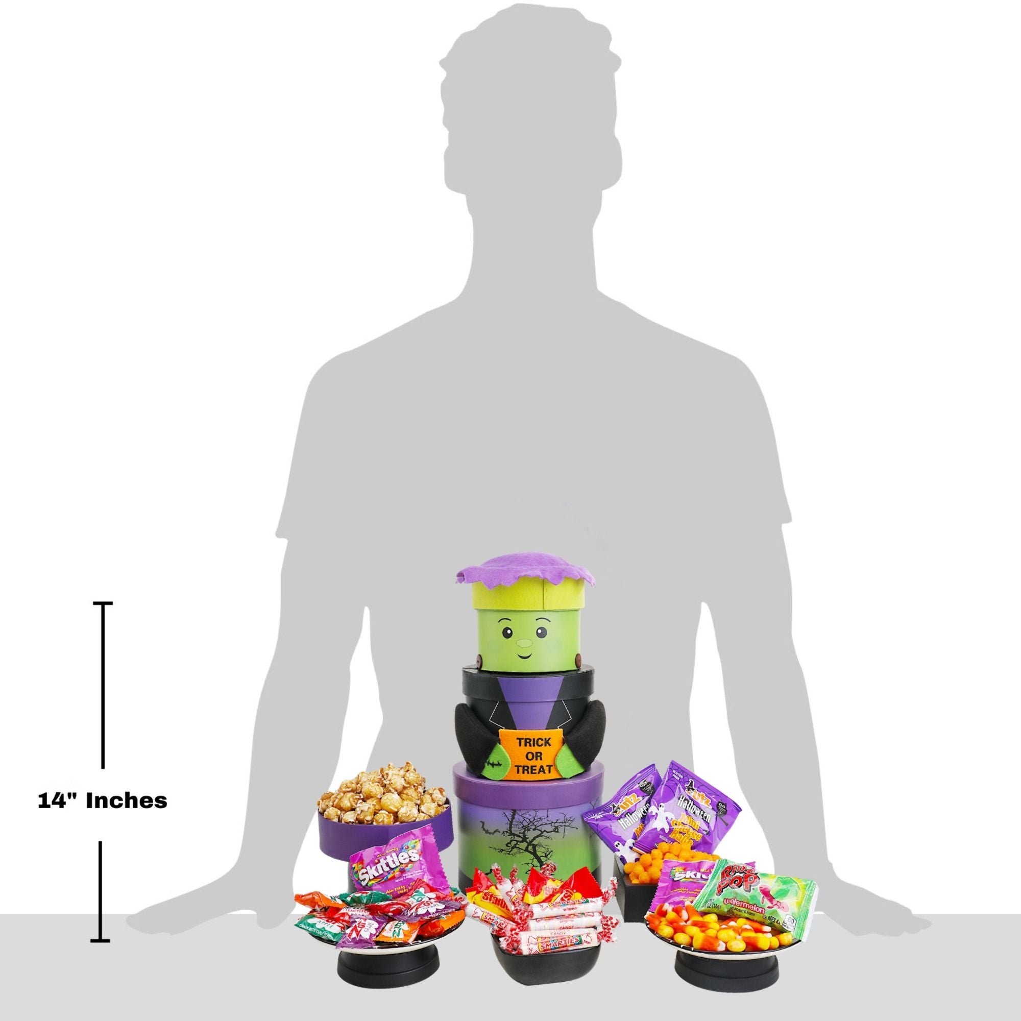 A Halloween-themed candy and snack display set shown in front of a gray human silhouette with a 14-inch height marker. The set includes three stacked containers with a Frankenstein design, a bowl of popcorn, and bags of assorted candies on a white background.