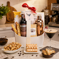 Gift basket with coffee-themed items including a bottle of Fever-Tree mix, a cocktail shaker, and a glass of espresso martini on a kitchen counter.