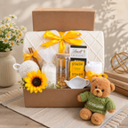 Gift basket with a teddy bear, sunflower, and tea items on a wooden surface.
