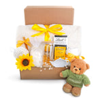 Gift basket with teddy bear, tea set, and snacks on a white background