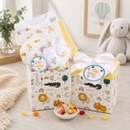 Two baby gift boxes with animal patterns on a table with a bowl of candy.