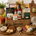 Gourmet gift basket with snacks, drinks, and charcuterie on a wooden table.