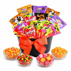 A Halloween-themed candy gift basket filled with assorted Skittles, and Starburst tied with a large orange bow in a black bucket, with four clear bowls of candy arranged in front on a white background.